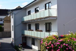 ein weißes Gebäude mit Balkonen und Blumen in der Unterkunft Gästehaus Am Hochsimmer in Ettringen