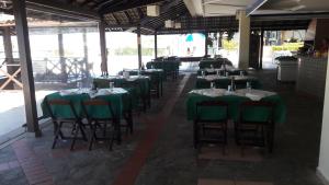 a row of tables with green clothed chairs in a restaurant at Apartamento Porto Real Brites in Mangaratiba