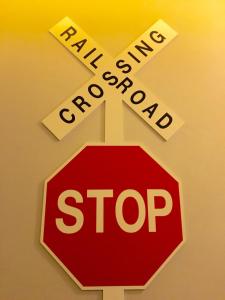 a stop sign in front of a railroad cross at The Museum Hotel in Nakhon Pathom