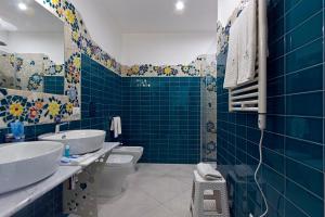 baño de azulejos azules con 2 lavabos y aseo en DubaiVillage, en Camposano