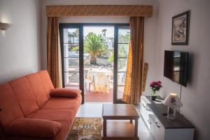 カレタ・デ・フステにあるBungalow Montecastillo 5のリビングルーム(オレンジ色のソファ、テーブル付)