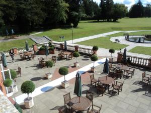 a patio with tables and chairs with umbrellas at Oakley Hall Hotel in Basingstoke