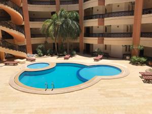 two people standing next to a swimming pool in a building at Regency Towers Apartments in Hurghada