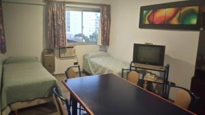 a room with two beds and a table and a tv at Apart Hotel Magali in Córdoba