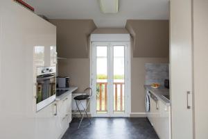una cocina con armarios blancos y una ventana en La Cerisaie en Saint-Malo
