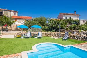 a pool with chairs and umbrellas in a yard at Holiday Home Lara in Brzac