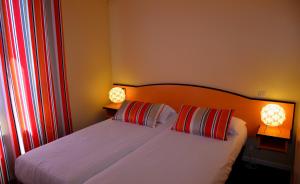 a bedroom with a bed with two lamps on it at Hotel Arc En Ciel in Èze