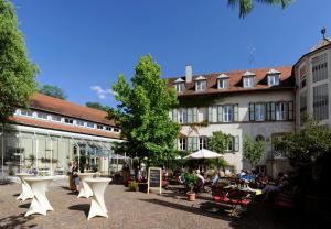 a group of people sitting in a courtyard in front of a building at Stiftsgut Keysermühle in Klingenmünster