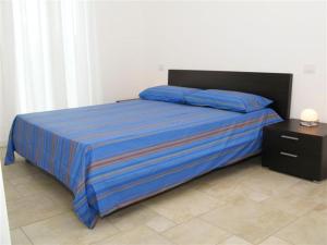 リド・ディ・イエゾロにあるResidence Mediterranee Family Apartmentsのベッド(青い掛け布団、ナイトスタンド付)