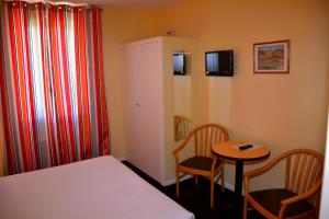 a small room with a bed and a table and chairs at Hotel Arc En Ciel in Éze