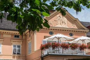 un edificio con balcón con sombrillas y flores en Hotel Elephant en Bressanone