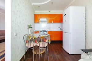 ロストフ・ナ・ドヌにあるApartments On Patsaeva 19/1 Dのキッチン(オレンジ色のキャビネット、テーブル、椅子付)
