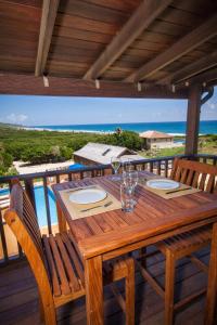 a wooden table on a deck with a view of the ocean at Santosha Barbados in Saint Andrew
