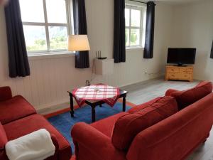 a living room with two red couches and a table at Liseth Pensjonat og Hyttetun in Garden