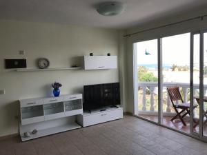 salon z telewizorem z płaskim ekranem i balkonem w obiekcie Vivienda Vacacional Maga w Corralejo