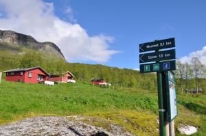 a street sign in a field with a red house at Liseth Pensjonat og Hyttetun in Eidfjord