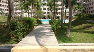un passaggio pedonale in un parco con palme e un edificio di Family Beach Condo PD at Cocobay Resort Condominium a Port Dickson