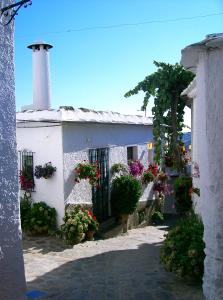 a white building with flowers and a lighthouse at Casita Buena Vista in Bubión
