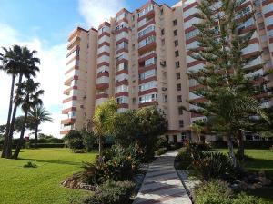 duży budynek apartamentowy z palmą przed nim w obiekcie La Corbeta w mieście Torrox Costa