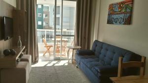 un soggiorno con divano blu e balcone di Residencial Encantos do Mar a Florianópolis