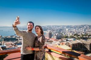 un homme et une femme prenant une photo d'une ville dans l'établissement Hotel Boutique Acontraluz, à Valparaíso