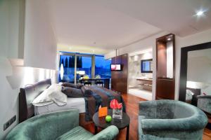 ein Schlafzimmer mit einem Bett und 2 Stühlen sowie ein Wohnzimmer in der Unterkunft Finca Prats Hotel Golf & Spa in Lleida