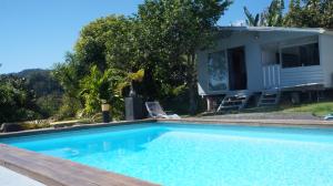 una piscina con una casa en el fondo en Bungalow Premium Tahiti en Punaauia