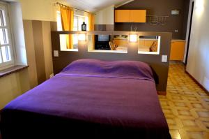 - une chambre avec un lit et une couverture violette dans l'établissement Al Lunario, à Cherasco