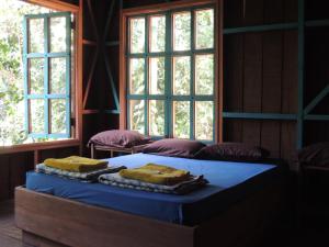uma cama num quarto com duas janelas em Yatama Rainforest Ecolodge em Sarapiquí
