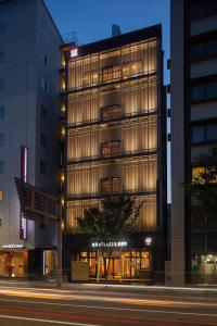 a tall building on a city street at night at Kanazawa Capsule Hotel Musashimachi in Kanazawa