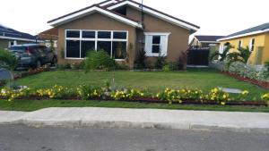 a house with yellow flowers in the front yard at Relax Villa in Ocho Rios