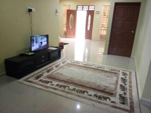 sala de estar con alfombra, TV y puerta en HR Iman Homestay, en Dungun