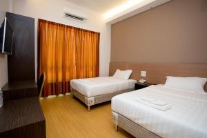 a hotel room with two beds and a television at Labuan Fortune Hotel in Labuan