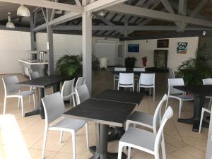 jadalnia ze stołami i białymi krzesłami w obiekcie Studio Vue Mer Village Soleil w mieście Le Gosier