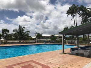a swimming pool with palm trees and a building at Charmant Studio Vue Mer Village Soleil in Le Gosier