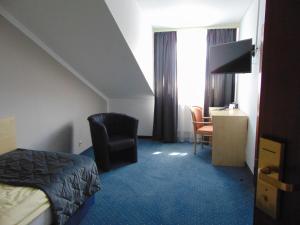 a hotel room with a bed and a chair and a desk at Hotel Restaurant Molitor in Bad Homburg vor der Höhe