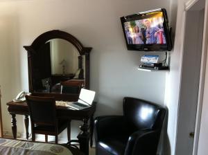 Habitación con escritorio y TV en la pared. en Motel Ritz en Gatineau