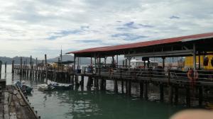 a dock with a building and boats in the water at Pangkor Home Sea Village in Pangkor