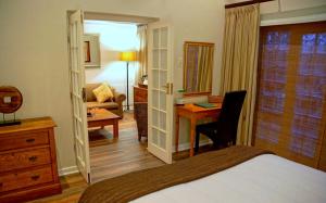 
a bedroom with a bed, chair, desk and a dresser at Wild Olive Guest House in Cape Town

