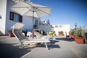 grupa krzeseł i parasol na patio w obiekcie B&B Baglio Santa Croce w mieście Porto Empedocle