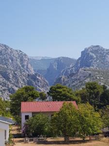 a house with a red roof with mountains in the background at Apartment Lavanda in Starigrad