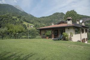 una pequeña casa en un campo con montañas en el fondo en Agriturismo Il Mirtillo B,B, en Pasturo