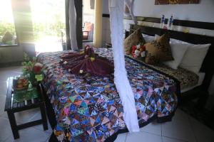 Una cama con edredón en una habitación en Putu Guest House Pemuteran en Pemuteran