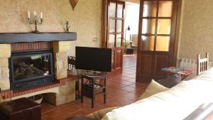 sala de estar con chimenea y TV en Alojamiento Turistico La Dehesa, en Las Navas del Marqués