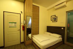 a small bedroom with a bed and a mirror at Shamrock Guest House II in Ipoh