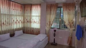 a bedroom with a bed and a window with curtains at Red Dragon Hotel in Hsipaw