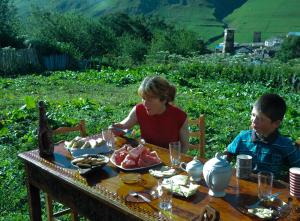 a woman and child sitting at a table with food at Guesthouse Angelina in Ushguli
