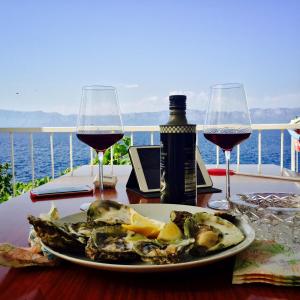 un piatto di cibo su un tavolo con due bicchieri di vino di Seafront Vacation home "Tea" a Trpanj (Trappano)