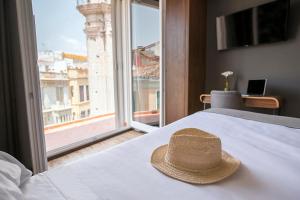 a hat sitting on top of a bed with a window at Málaga Premium Hotel in Málaga