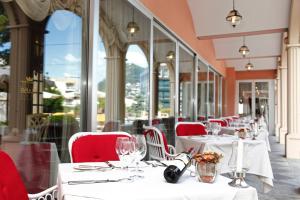 a restaurant with white tables and red chairs and windows at Hotel De La Paix in Lugano